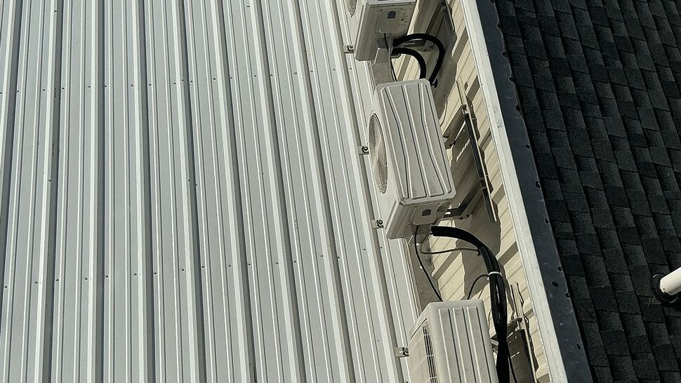 Row of roof-mounted HVAC units installed along the side of a white metal roof.