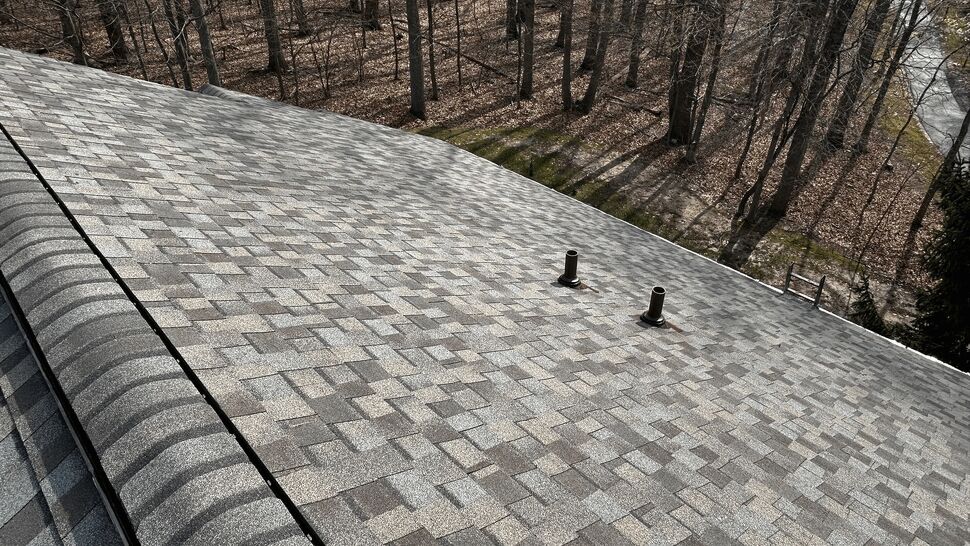 Close-up of a shingled roof slope with two plumbing vents and flashing.