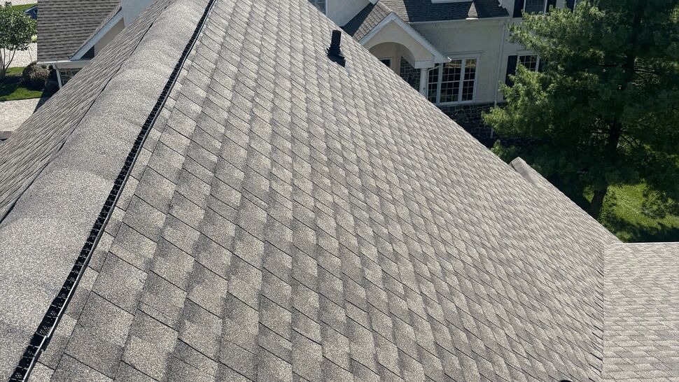 Close rooftop perspective along the shingle ridge with roof vent and chimney visible.