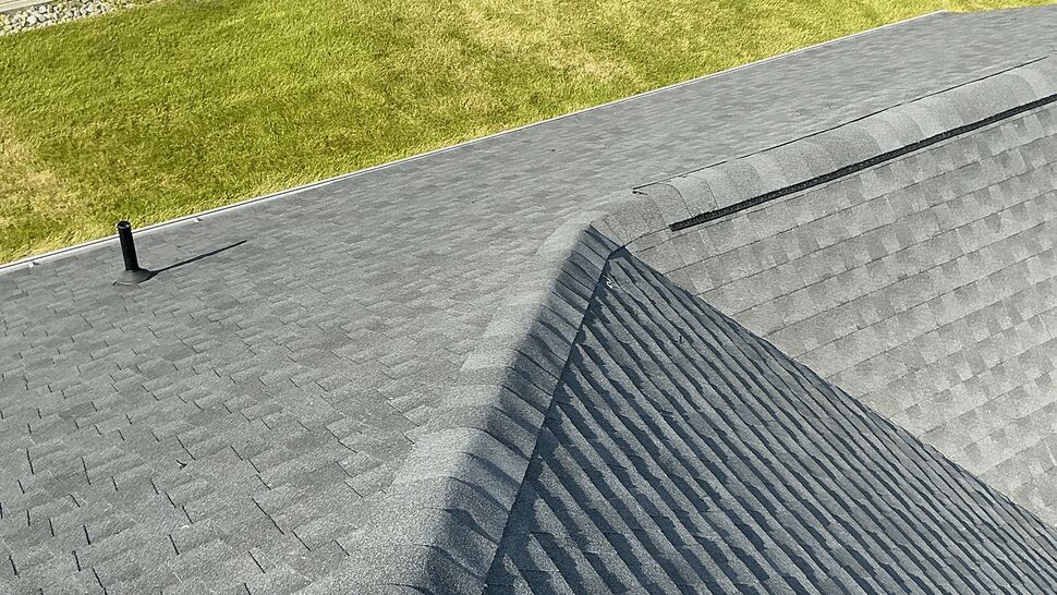 Close-up of gray shingle ridge with ridge vent on residential roof