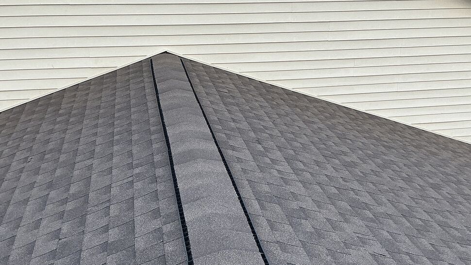 Shingled roof peak with a continuous ridge vent running along the ridge.