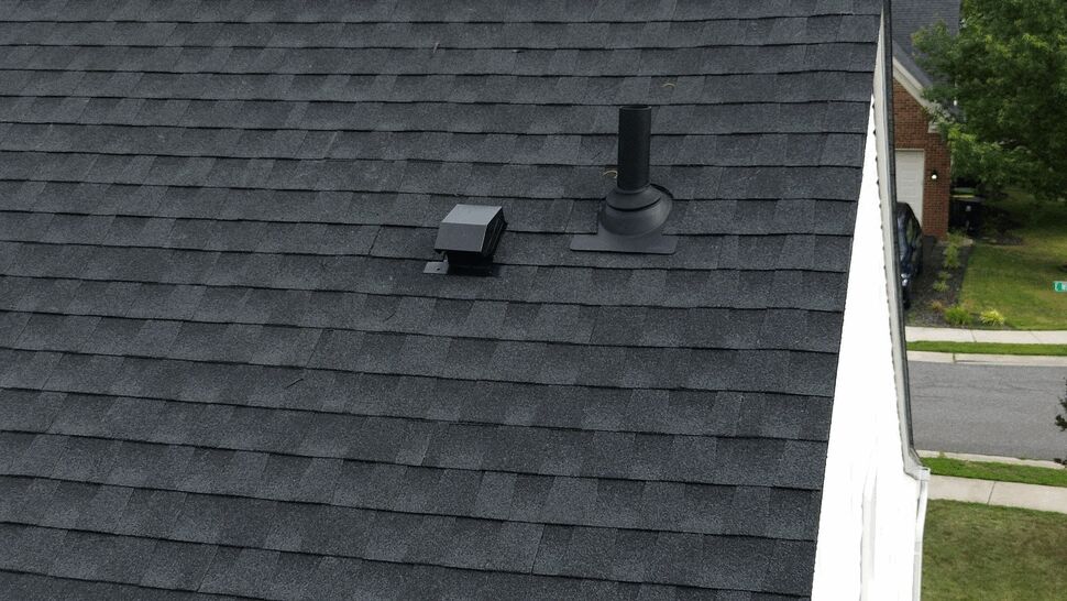Close-up of roof shingles with a vent pipe and roof cap flashing.