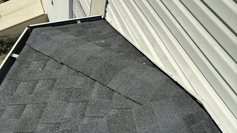 Close-up of shingles meeting vinyl siding at a roof junction