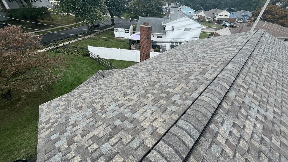 Roof valley and ridge lines on a grey shingle roof overlooking the backyard.