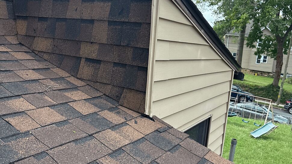 Roof valley meeting beige siding at a roof-to-wall junction
