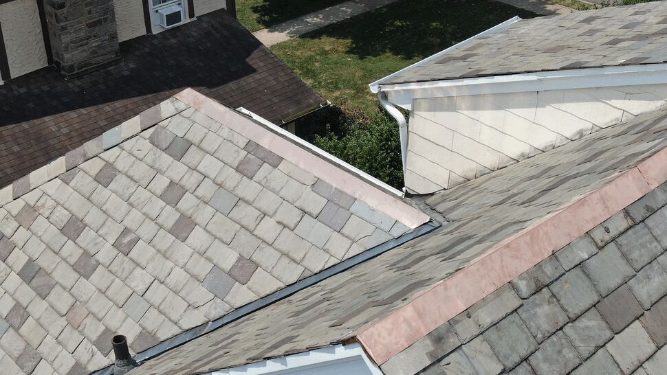 Close-up of a copper-flashed roof valley and adjacent white gutter.