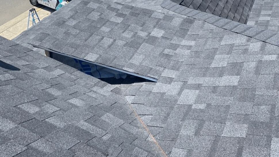 Roof valley with vent pipe and newly laid asphalt shingles