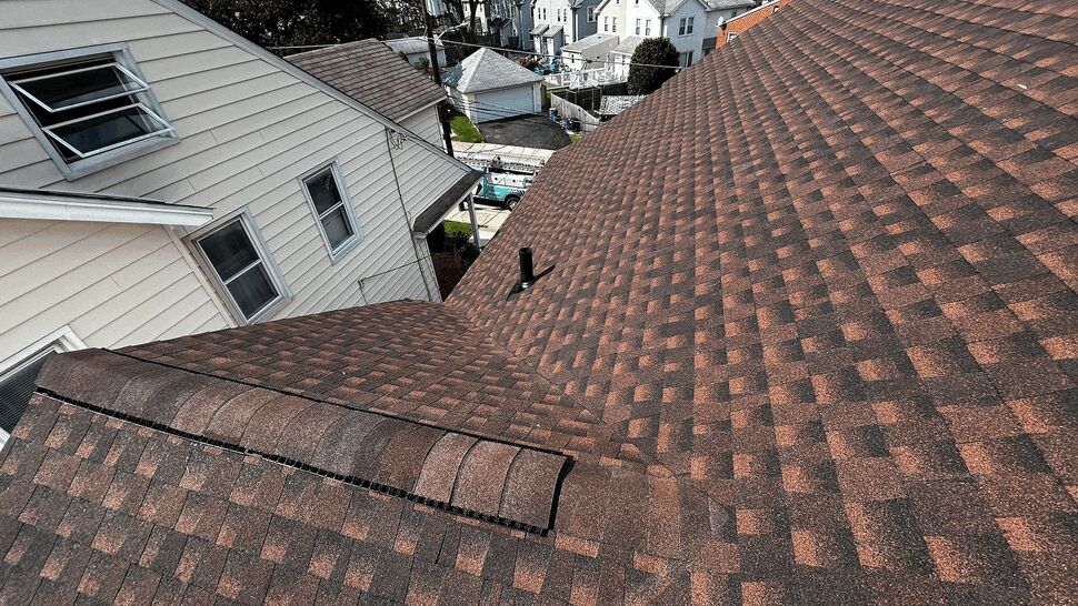 Roof valley with vent pipe between houses and neighborhood in background