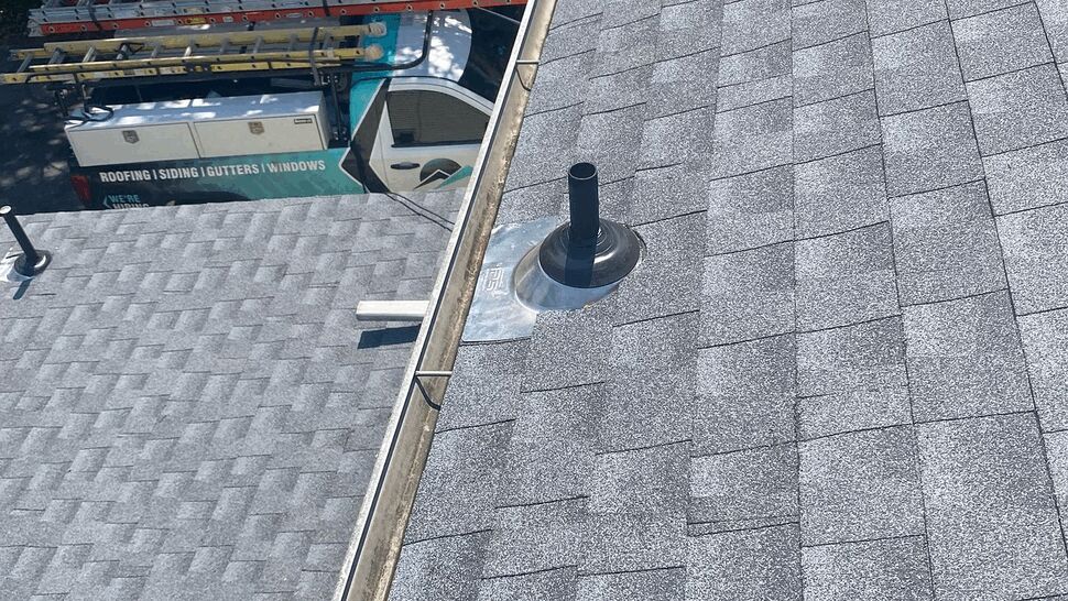 Gray shingle roof with a metal vent and roofing service truck below