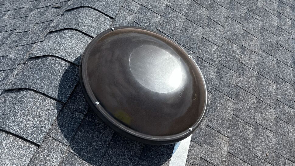 Round rooftop vent dome mounted on asphalt shingles.