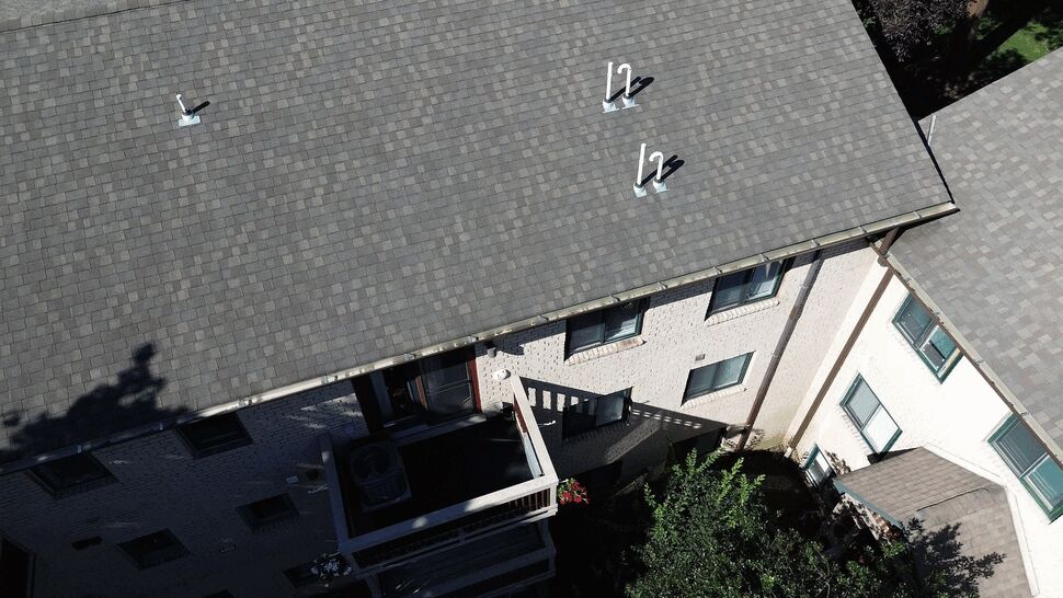 Aerial roof vents and gutters | Tycos Roofing And Siding Inc Overhead shot of asphalt shingle roof with multiple plumbing vents and gutters.