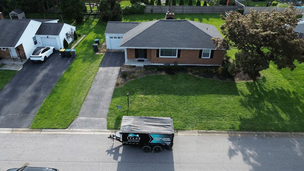 Aerial Street View with Trailer | Tycos Roofing And Siding Inc Aerial view of a house with a Tycos Roofing And Siding Inc trailer parked on the street.