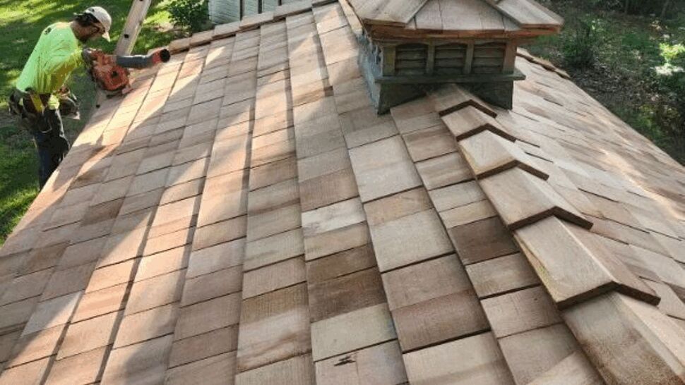 Roofing crew installing cedar shingles | Tycos Roofing And Siding Inc Worker installing cedar shingles on a gazebo roof with a small cupola.