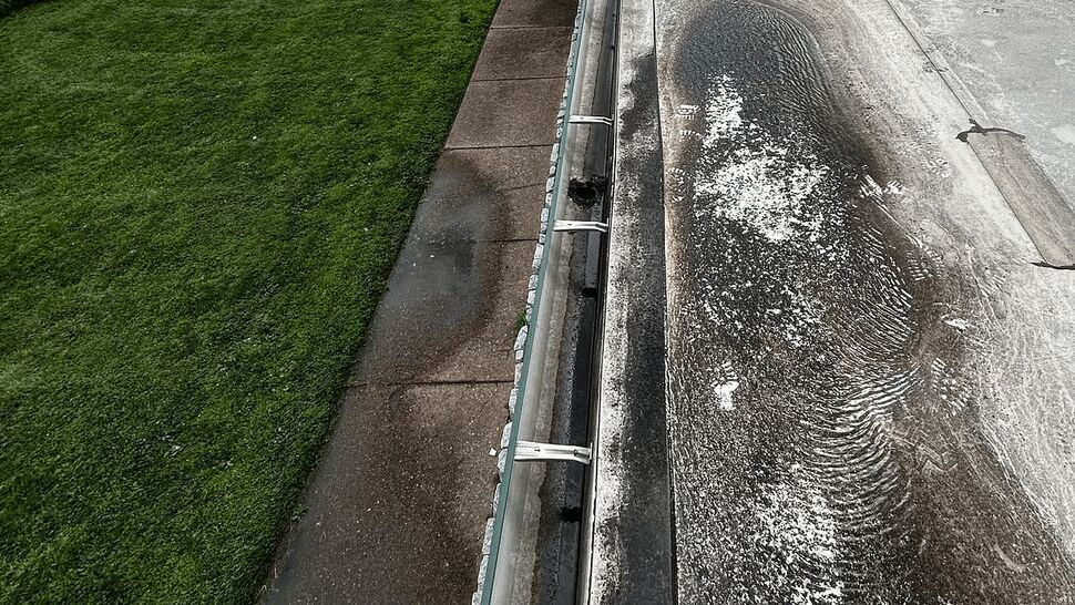 Roof Ponding and Gutter View | Tycos Roofing And Siding Inc Long roofline with gutter and large ponding stains on a flat commercial roof