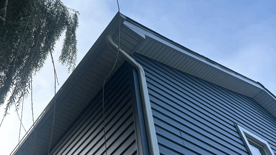 Close-up of roofline, soffit, gutter and blue siding from ground angle