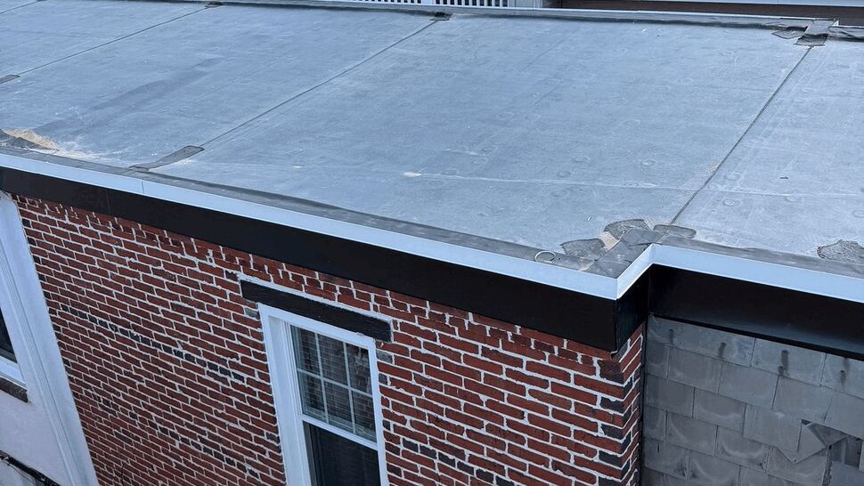Flat rooftop with neighboring deck railings and brick exterior wall