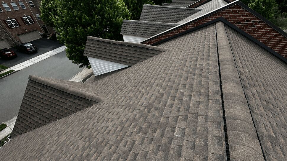 Aerial view of multiple gabled asphalt shingle roofs and ridges