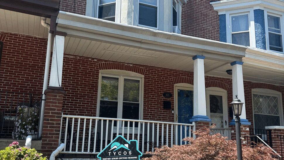 Brick rowhome porch with a yard sign for Tycos in front of landscaped steps.