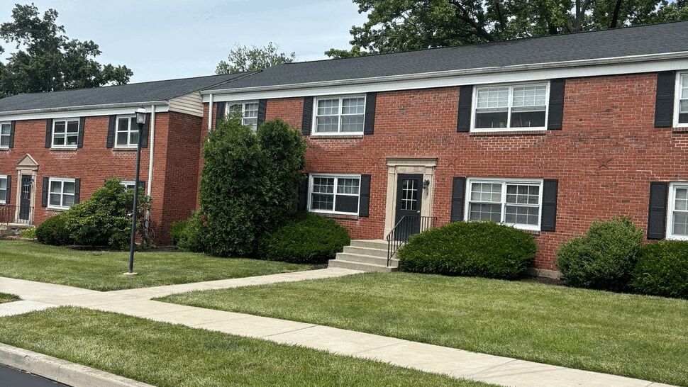 Long row of brick townhouses with dark shingle roof and trimmed landscaping
