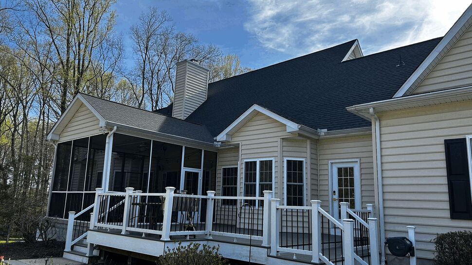 Back deck with white railing and screened porch attached to beige house