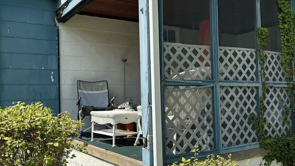 Screened Porch Renovation | Tycos Roofing And Siding Inc Older screened porch with blue siding, lattice panels, and garden plants