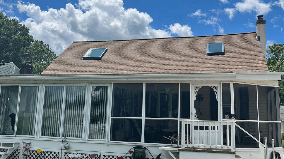 Back of house with screened porch four-season room and skylights on roof