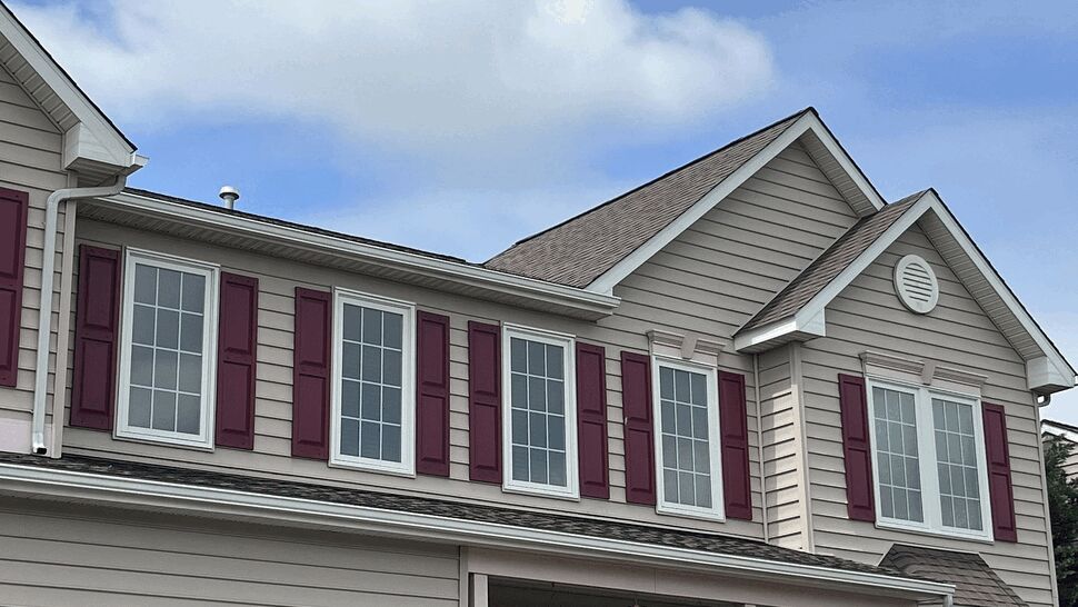 Close-up of second-floor windows with burgundy shutters and white trim