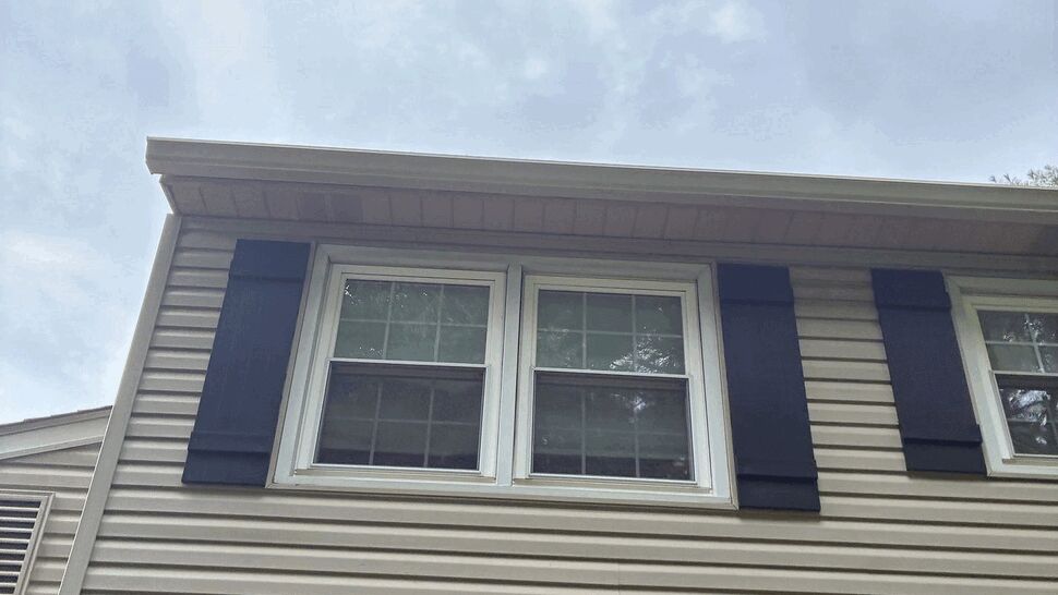 Second-floor windows with vinyl siding | Tycos Roofing And Siding Inc Second-floor double windows with dark shutters and vinyl siding