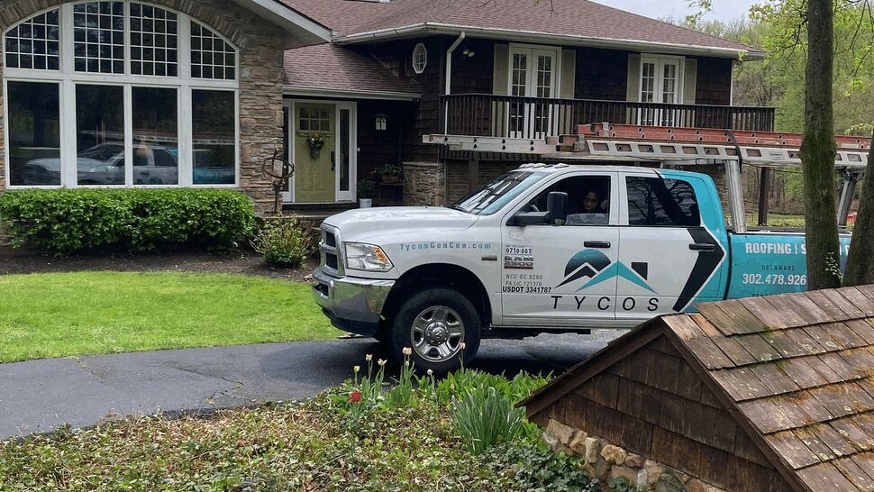 Tycos service truck parked in front of a suburban home with ladder and roofing sign