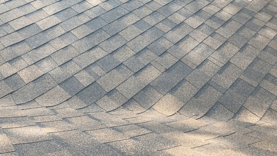 Close-up of asphalt shingles showing buckling and granule loss