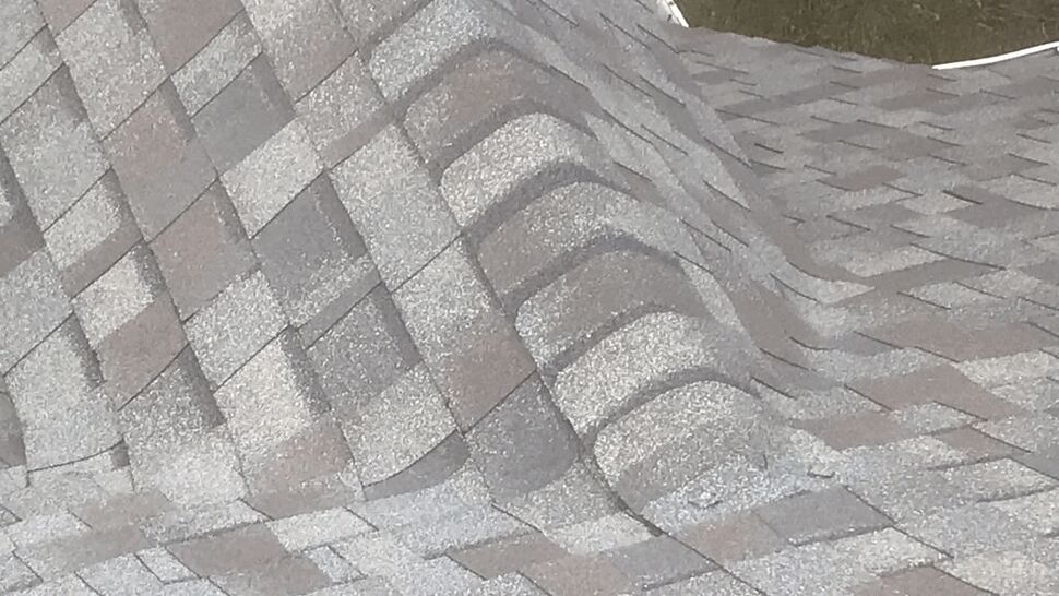 Buckled Shingles at Roof Ridge | Tycos Roofing And Siding Inc Close-up of buckled asphalt shingles along a roof ridge