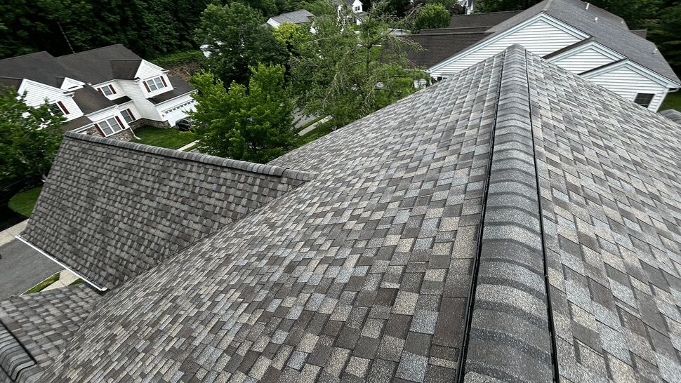 Close-up aerial view of roof ridge with gray architectural shingles and ridge vent
