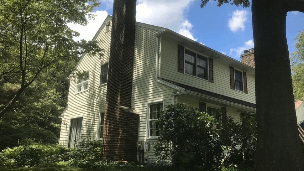 Side Chimney with Gutters and Siding | Tycos Roofing And Siding Inc Side view of house showing brick chimney, siding and gutter line.