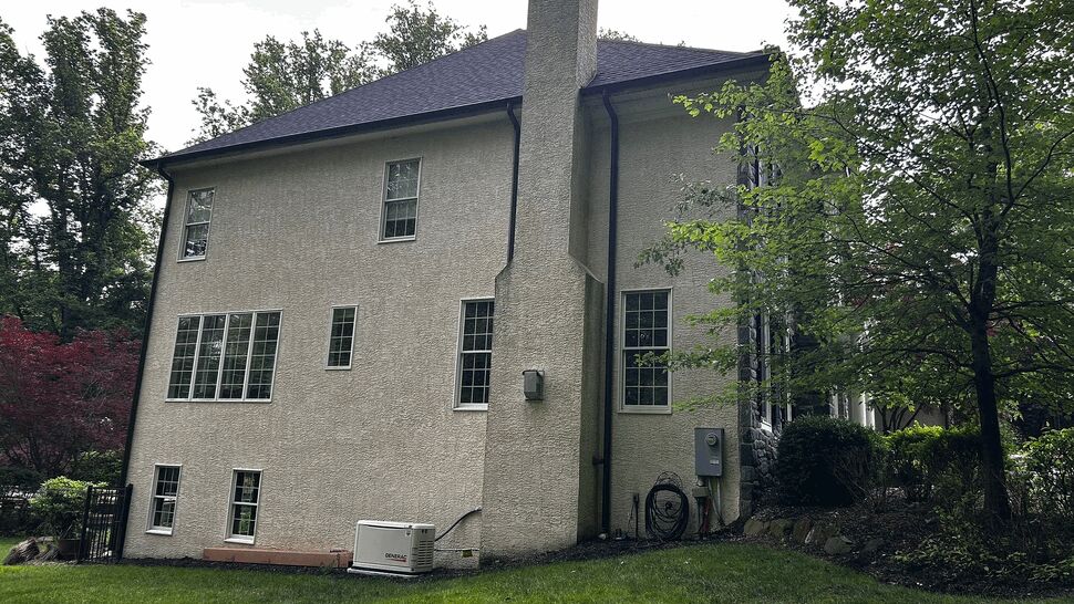 Side elevation of stucco house with chimneys, downspout and generator