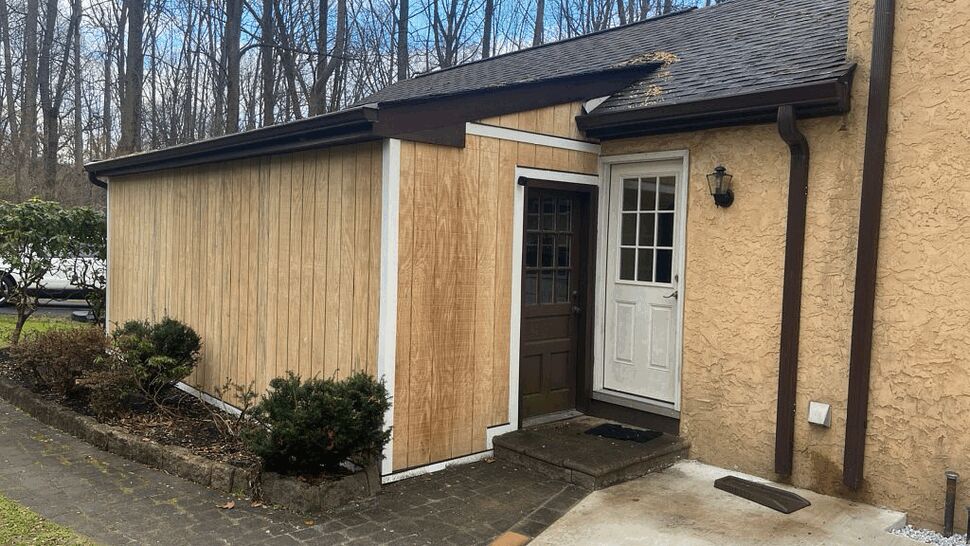 Side entry showing white door, dark trim and vertical wood siding panels.