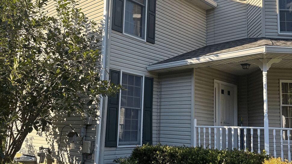 Side view of home showing white gutter, downspout, windows and landscaped flower bed.