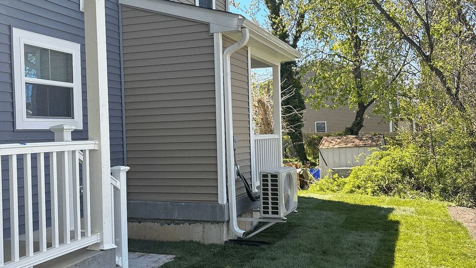Side view of house showing siding, porch, downspout and grassy yard.