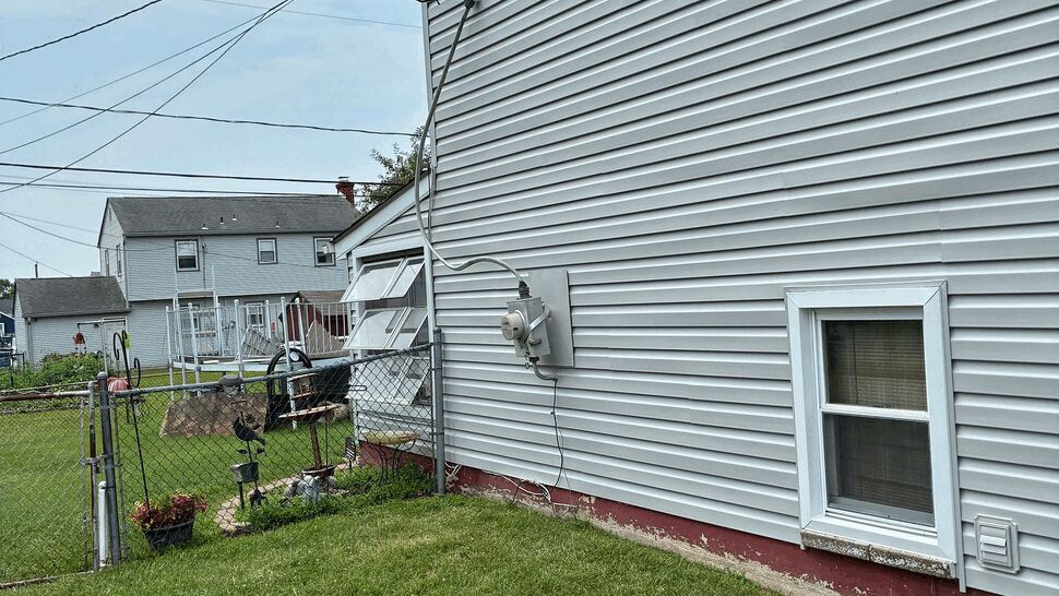 Side elevation with vinyl siding, electrical meter, and small basement window