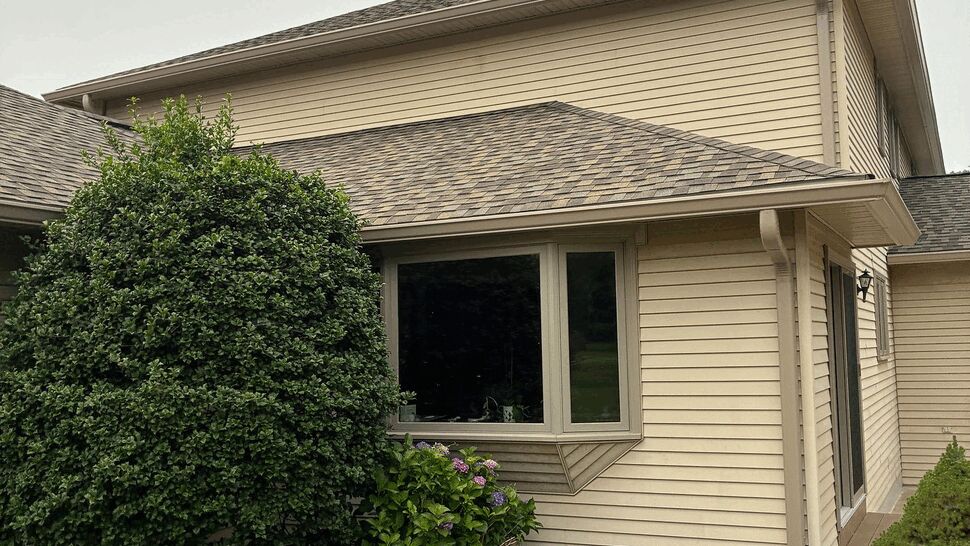 Bay window set in beige siding with landscaping in front.