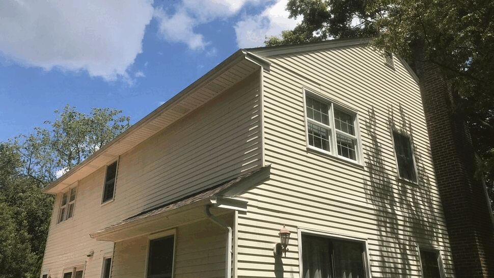 Siding and Window Close-Up with Gutters | Tycos Roofing And Siding Inc Close-up of vinyl siding, windows, soffit and gutter under blue sky.