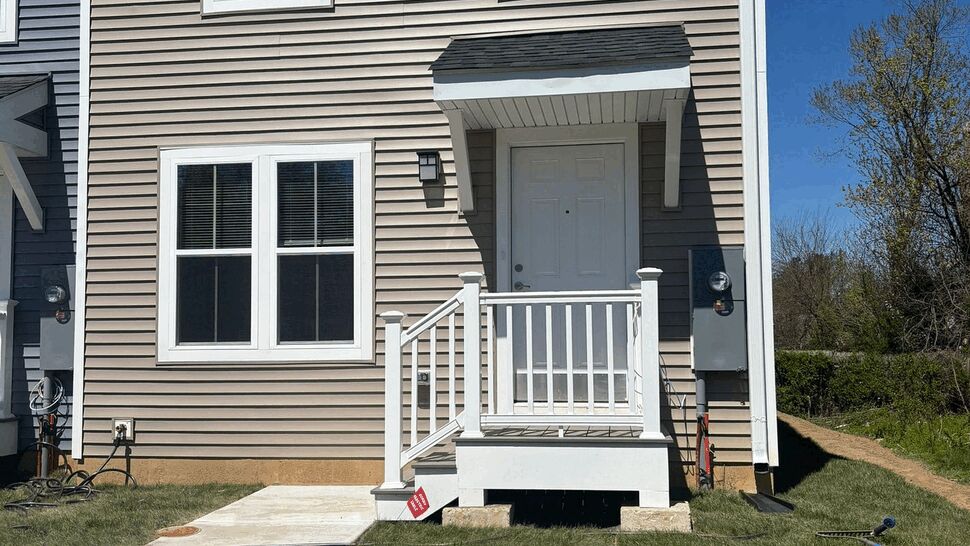 Close-up of townhouse front door, small porch and concrete walkway.