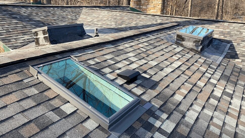 Roof skylight installation | Tycos Roofing And Siding Inc Single rectangular skylight installed on asphalt shingle roof near chimneys.