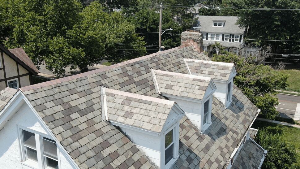 Aerial view of a slate roof with three white dormers.