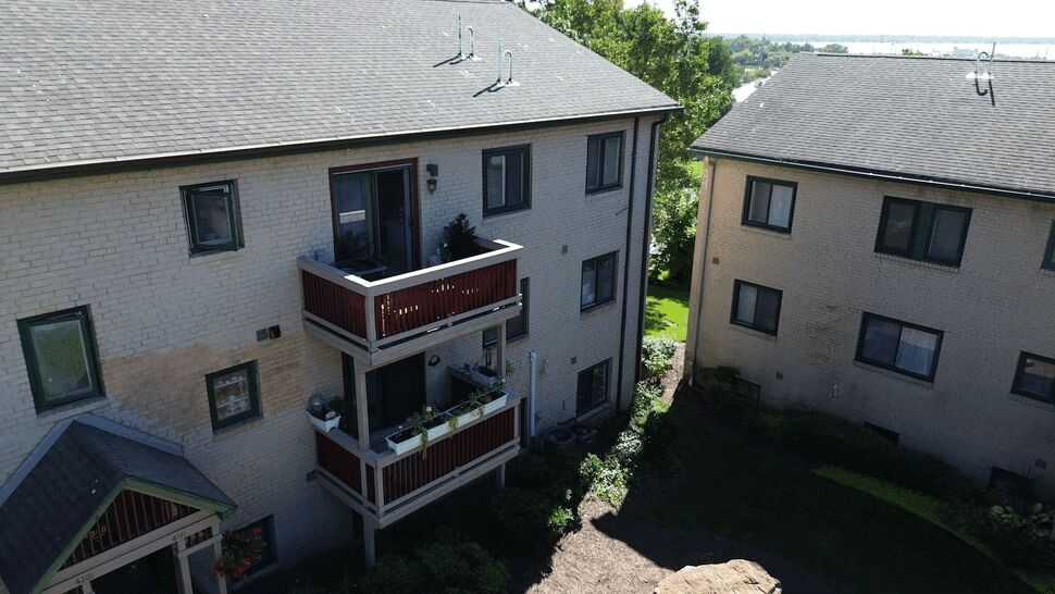 Stacked balconies and railings | Tycos Roofing And Siding Inc Two stacked wooden balconies with planters and railings on a brick building.