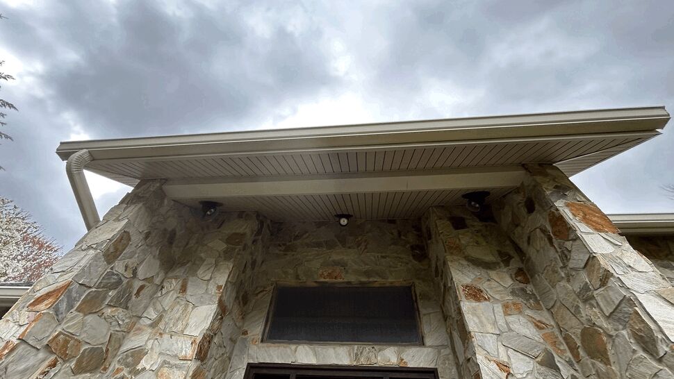 Stone entryway with overhanging soffit and rain gutter