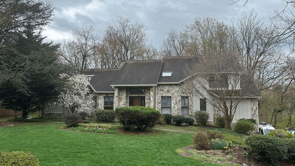 Front view of stone house with pitched roof and landscaped lawn