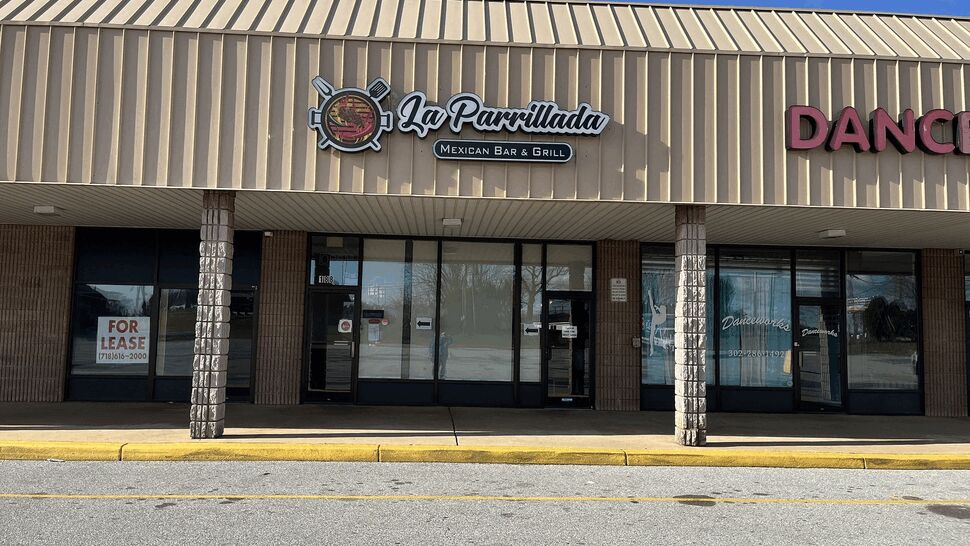 Strip mall storefront entrance | Tycos Roofing And Siding Inc Strip mall storefront with metal canopy and glass doors.