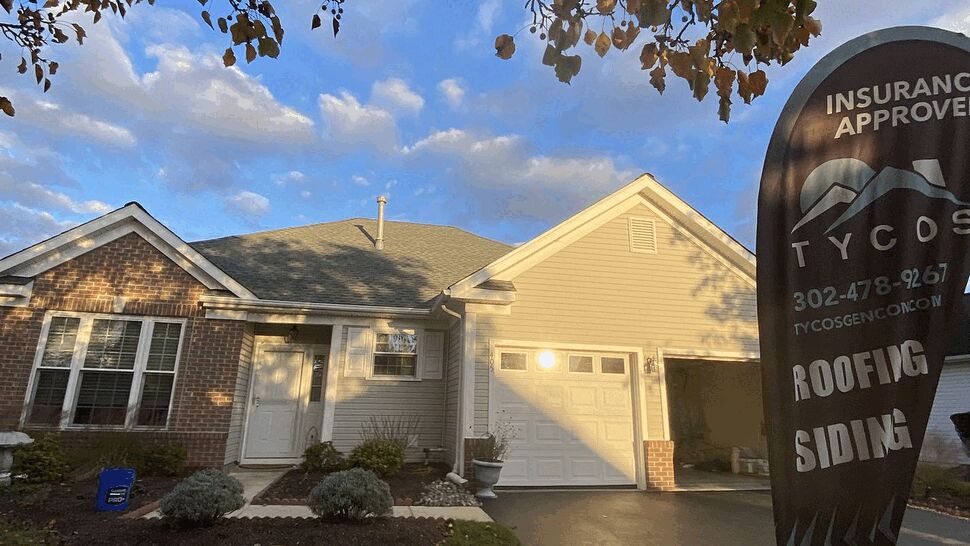 Front home with Tycos roofing flag | Tycos Roofing And Siding Inc Front of a single-story house with a Tycos flag advertising roofing and siding.