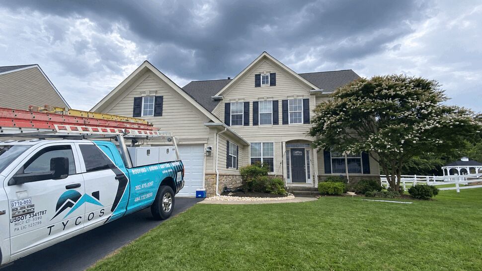Front of two-story house with Tycos truck parked in driveway under a cloudy sky