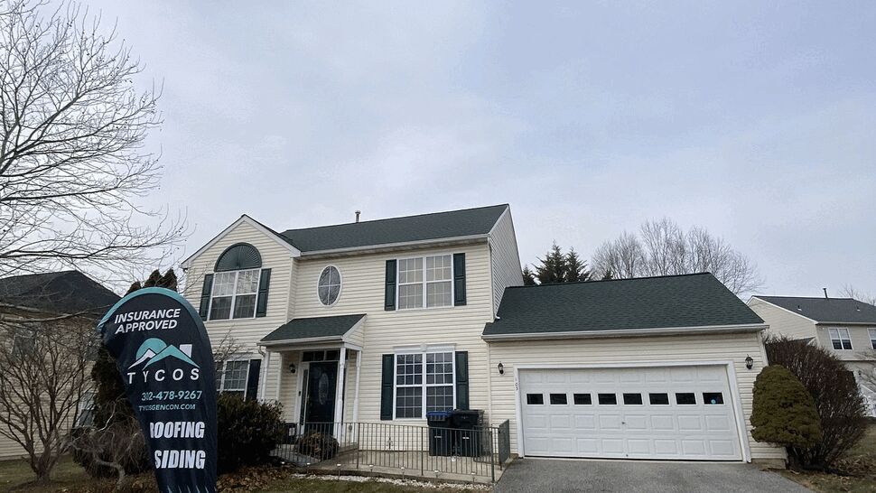 Two-story suburban home with Tycos sign on lawn and dark roof.
